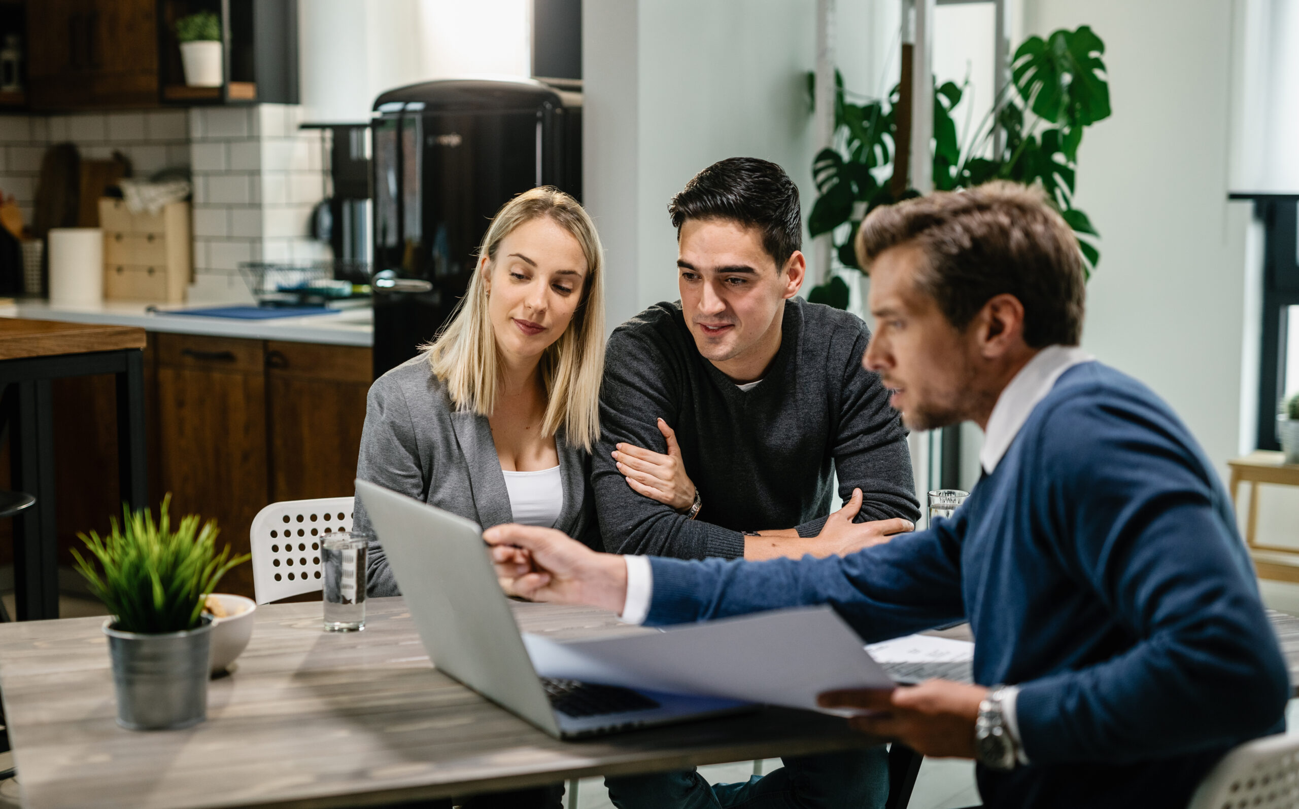 Smiling couple using a computer with their investment agent on a meeting. persoonlijk gesprek over werken en ziek zijn